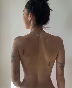 a woman with tattoos on her back standing in front of a mirror