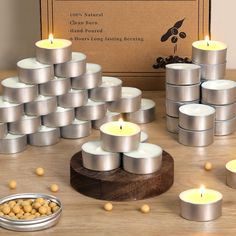 many candles are arranged on a table next to some tins with nuts in them