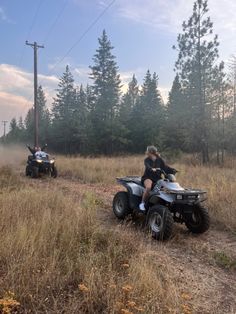 two people riding four wheelers on a dirt road