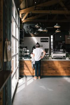 a man standing in front of a counter at a coffee shop with lots of lights hanging from the ceiling