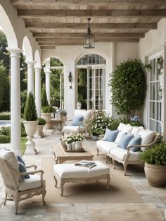 an outdoor living area with white furniture and potted plants on either side of the patio