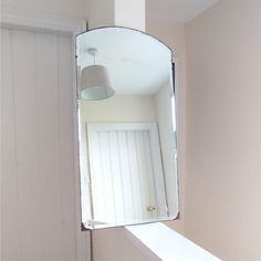 a mirror hanging on the side of a wall next to a white window sill