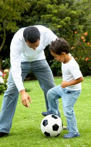 a father and son playing with a soccer ball