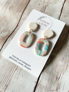 the earrings are made from polymer and have colorful designs on them, including an oval shaped ear