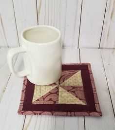 a coffee mug sitting on top of a place mat next to a white cup holder