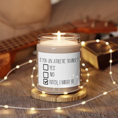 a candle that is sitting on a table with some string lights and a guitar in the background