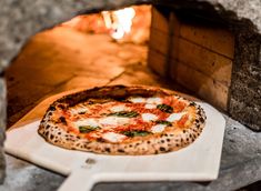 a cheetah pizza is being cooked in an outdoor wood fired oven with the door open