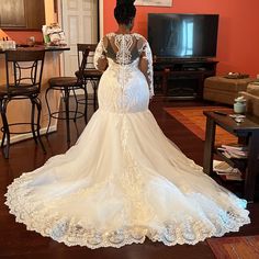 a woman in a wedding dress looking back at the camera while standing in a living room