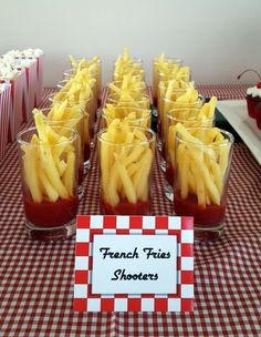 french fries are arranged in glasses on a table with red and white checkered cloth