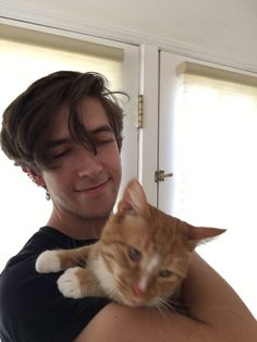 a man holding an orange and white cat in his arms