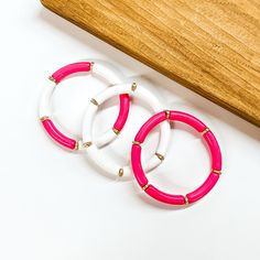 This is a set of three tube bracelets in white and hot pink with gold spacers. From left to bottom; hot pink and white tubes, white tubes, hot pink tubes. This bracelet set is taken on a white background with a slab of wood in the back as decor. Tube Bracelet, Giddy Up Glamour, We Are Love, Pink Jewelry, Full Look, In Hot, Pink And White, Bracelet Set, Favorite Outfit