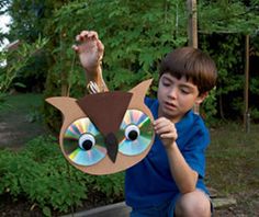 a young boy holding an owl shaped cutout with cds in it's eyes