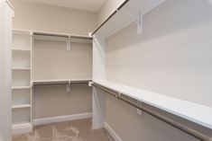 an empty walk in closet with white walls and shelving unit on the right side