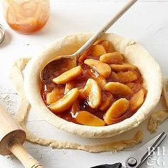 a pie crust with apples in it on a table next to some utensils