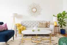 a living room with white couches, blue chairs and a large sunburst on the wall