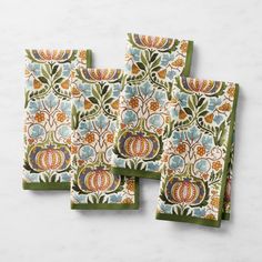 four napkins with pumpkins and leaves on them in green, orange and blue