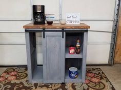 a small table with a coffee maker on top and some spices in the bottom drawer