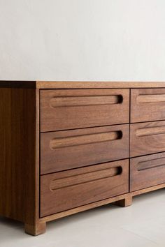 a close up of a wooden dresser on a white floor with a wall in the background