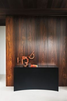 an empty room with wood paneling on the walls and a black table in front of it