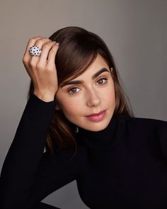 a woman wearing a black turtle neck top and holding a dice in her right hand