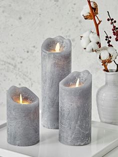 three grey candles sitting on top of a white tray