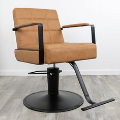 a tan leather office chair sitting on top of a black metal base in front of a white wall