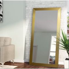 a large gold framed mirror sitting on top of a wooden floor next to a chair