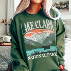 Show off your love of Alaska and one of our nation's most remote national parks with our Lake Clark National Park Sweatshirt! This comfy crewneck is all about embracing the great outdoors, featuring a custom vintage design that showcases the grandeur of the Alaskan Wilderness, the iconic Brown Bear, and the beautiful vistas across Lake Clark! The Gildan 18000 50/50 blend fabric has that comfy, lived-in feel, that's like a hug every time you put it on! Now you can take a bit of Lake Clark with yo National Park Sweatshirt, California Sweatshirt, National Park Gifts, National Park Shirt, Great Smoky Mountains National Park, Beautiful Park, Smoky Mountain National Park, A Hug, Limassol