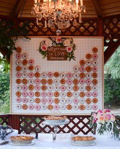 a table topped with pies under a chandelier next to a wooden fence