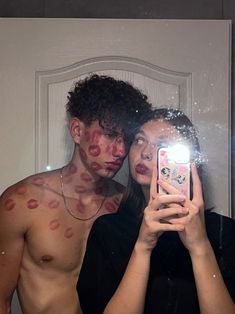 a man and woman taking a selfie in front of a mirror with red spots on their body