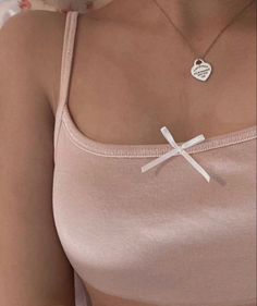 a woman wearing a pink top with a cross pendant on her chest and a necklace that says i love you