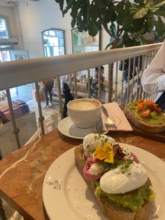 a plate with food on it sitting on a table next to a cup of coffee