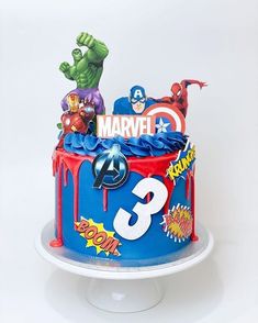 a birthday cake decorated with the avengers symbol and other cartoon characters on top of it