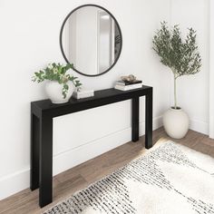 there is a black table with a mirror on it next to a potted plant