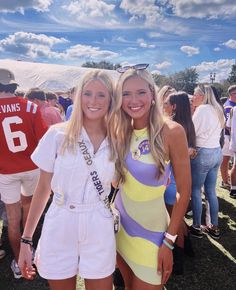 two beautiful young women standing next to each other in front of a group of people