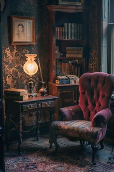 a red chair sitting in front of a window next to a desk with a lamp on it