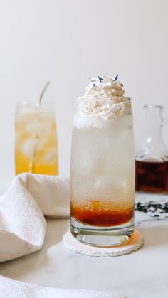 two glasses filled with drinks sitting on top of a table next to white towels and napkins