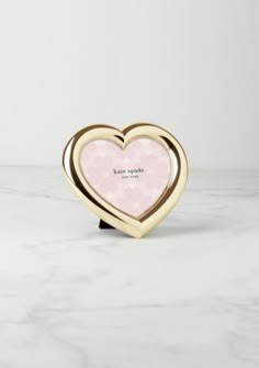 a pink and gold heart shaped object on a white marble surface with the words love sparkle written