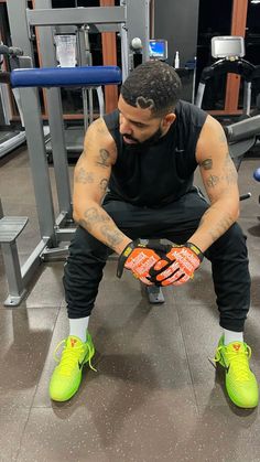 a man sitting on top of a gym floor with his hands in the air and wearing neon green shoes