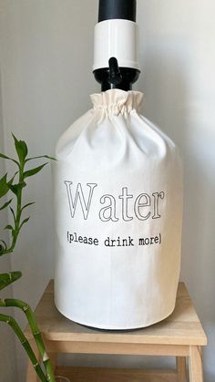 a white bag that has water in it on top of a wooden table next to a potted plant