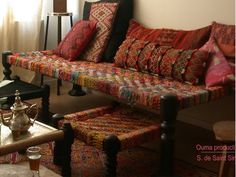 a living room filled with lots of colorful pillows and blankets on top of a couch