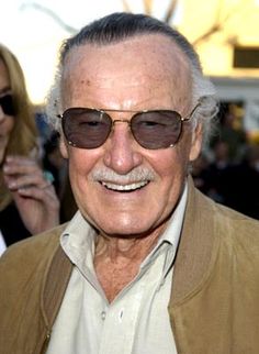 an older man wearing sunglasses and smiling at the camera with people around him in the background