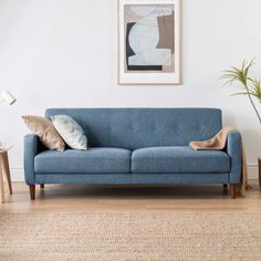 a blue couch sitting in a living room next to a wooden table and planter