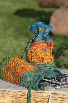 a knitted bag sitting on top of a wooden bench next to a pair of scissors