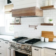 a stove top oven sitting inside of a kitchen next to white cabinets and counter tops