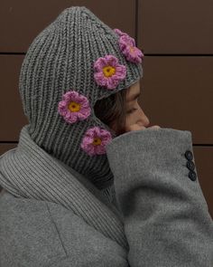 a woman wearing a gray hat with pink flowers on it's side and her face to the side