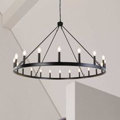 a circular chandelier with candles hanging from it's center ring in an empty room