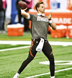 a man holding a football on top of a field with other people in the background