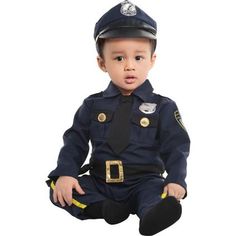 a baby dressed in a police uniform sitting on the ground