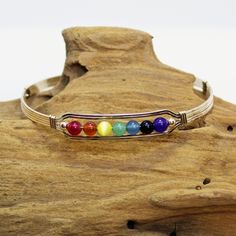 "A contemporary little bracelet of five strands of 14kt gold filled wire with a center design featuring the seven colors of the chakra in 4mm beads, accented with two smaller gold beads. Perfect for the girl who loves to get her \"metaphysical\" on! Stackable, too, along with many of my other wirewrapped bracelets! The sturdy built-in hook and eye clasp is easy to get on and off by yourself. Choose the size you need for a comfortable custom fit." Nickel Free Gold Beaded Bracelets In Sterling Silver, Nickel-free Gold Beaded Bracelets In Sterling Silver, Adjustable Wire Wrapped Wrap Bracelet Bangle, Adjustable Wire Wrapped Wrap Bracelet, Adjustable Spiritual Gold Jubilee Bracelet, Adjustable Hand Wrapped Spiritual Bangle, Gold Spiritual Wire Wrapped Cuff Bracelet, Handmade Adjustable Spiritual Gold Bracelet, Adjustable Wire Wrapped Spiritual Cuff Bracelet